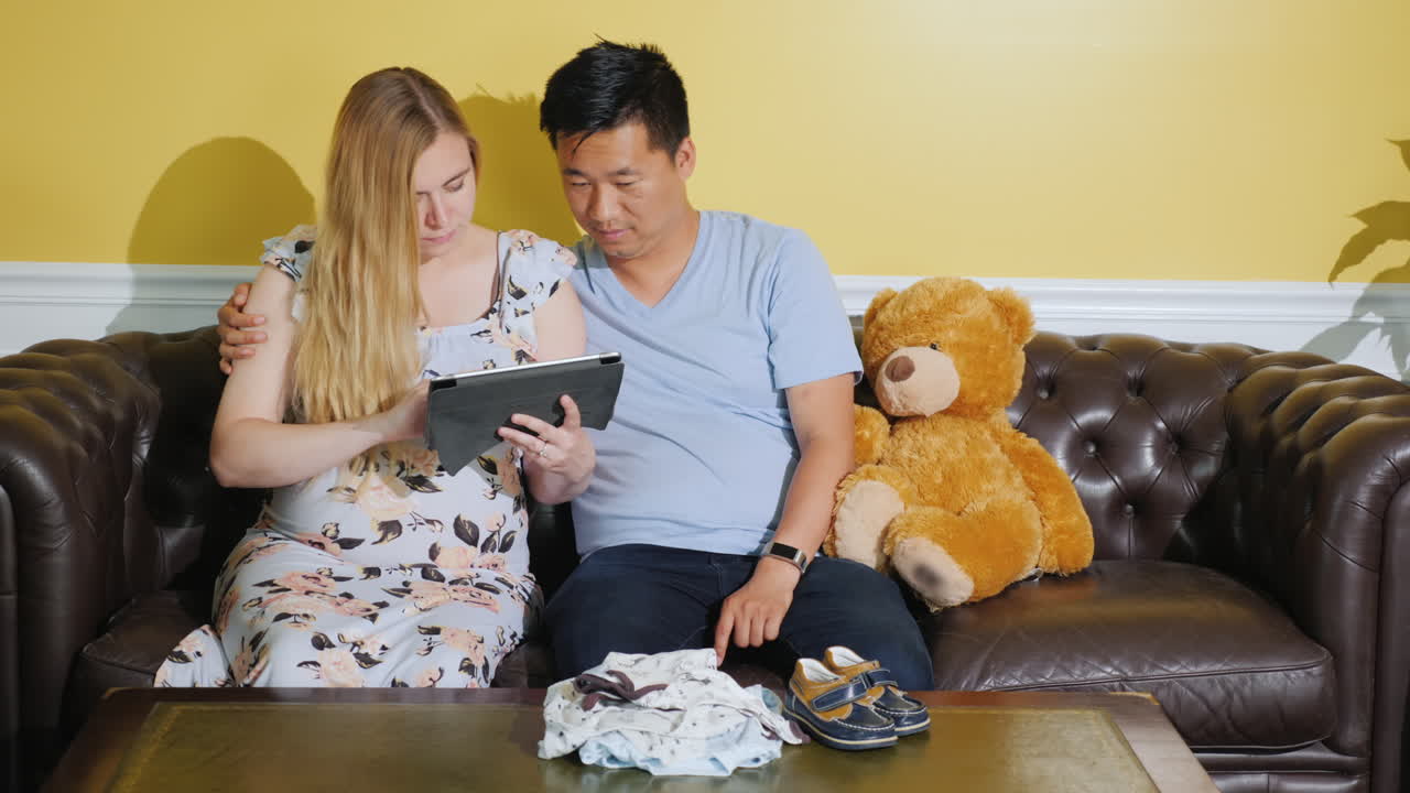 젊은 가족이 미래의 아기 사용 태블릿을 위해 물건을 주문합니다.