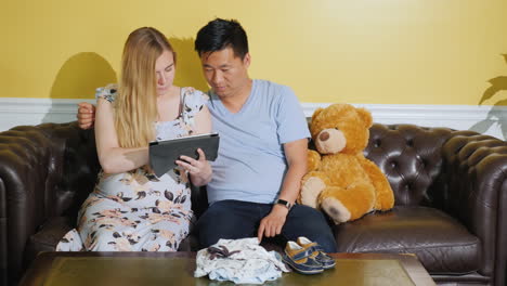 a young family orders things for their future baby use tablet