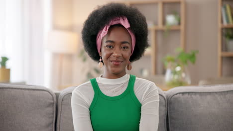 a young african woman with a bright smile and head scarf sitting on a couch