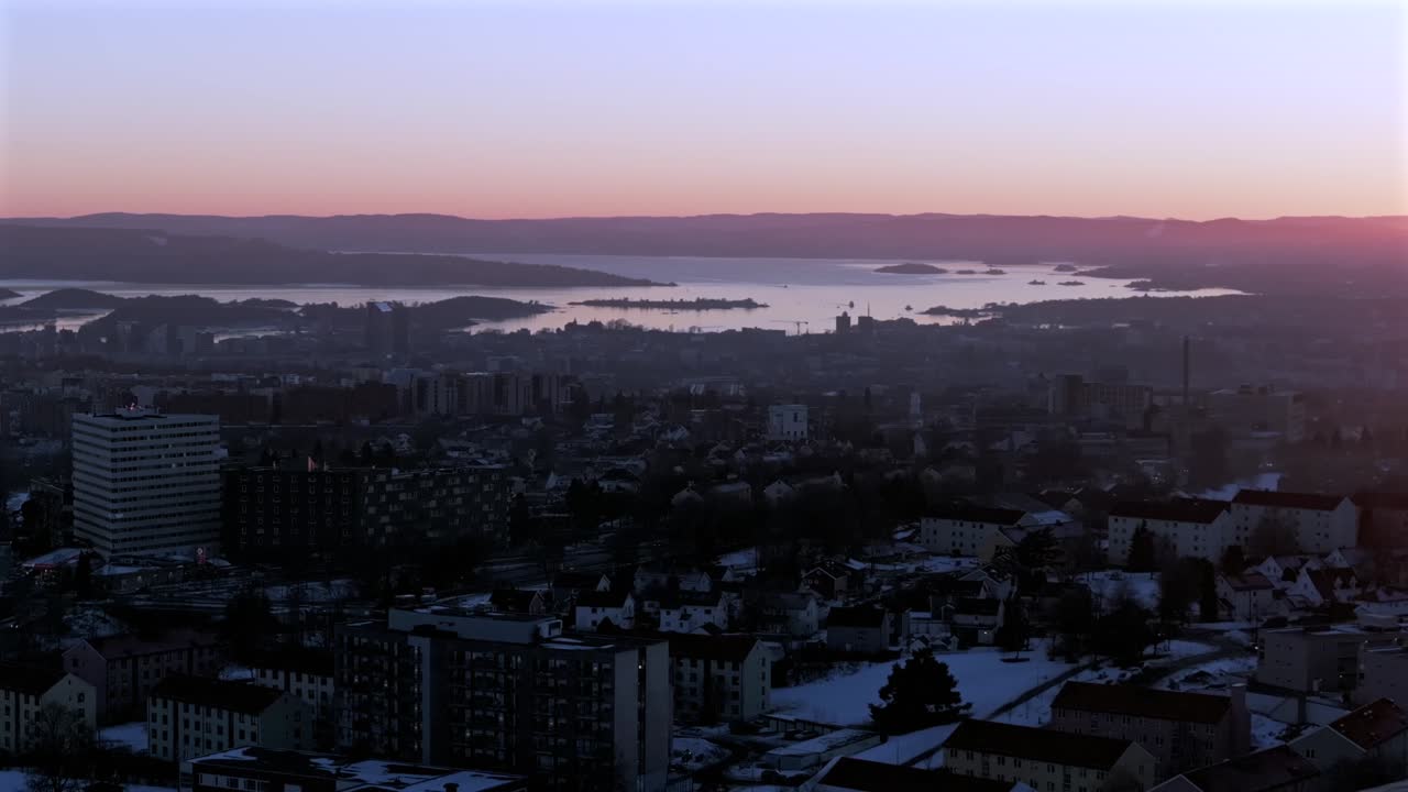 Downtown Oslofjord Olso city Norway Norge aerial drone view inner coastline Hovedøya Lindøya islands Norwegian arctic vibrant pink purple hue sunset apartment buildings cityscape parallax circle right