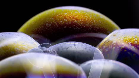 Close-up-image-of-soap-bubbles-on-a-black-background,-golden-iridescent-surfaces