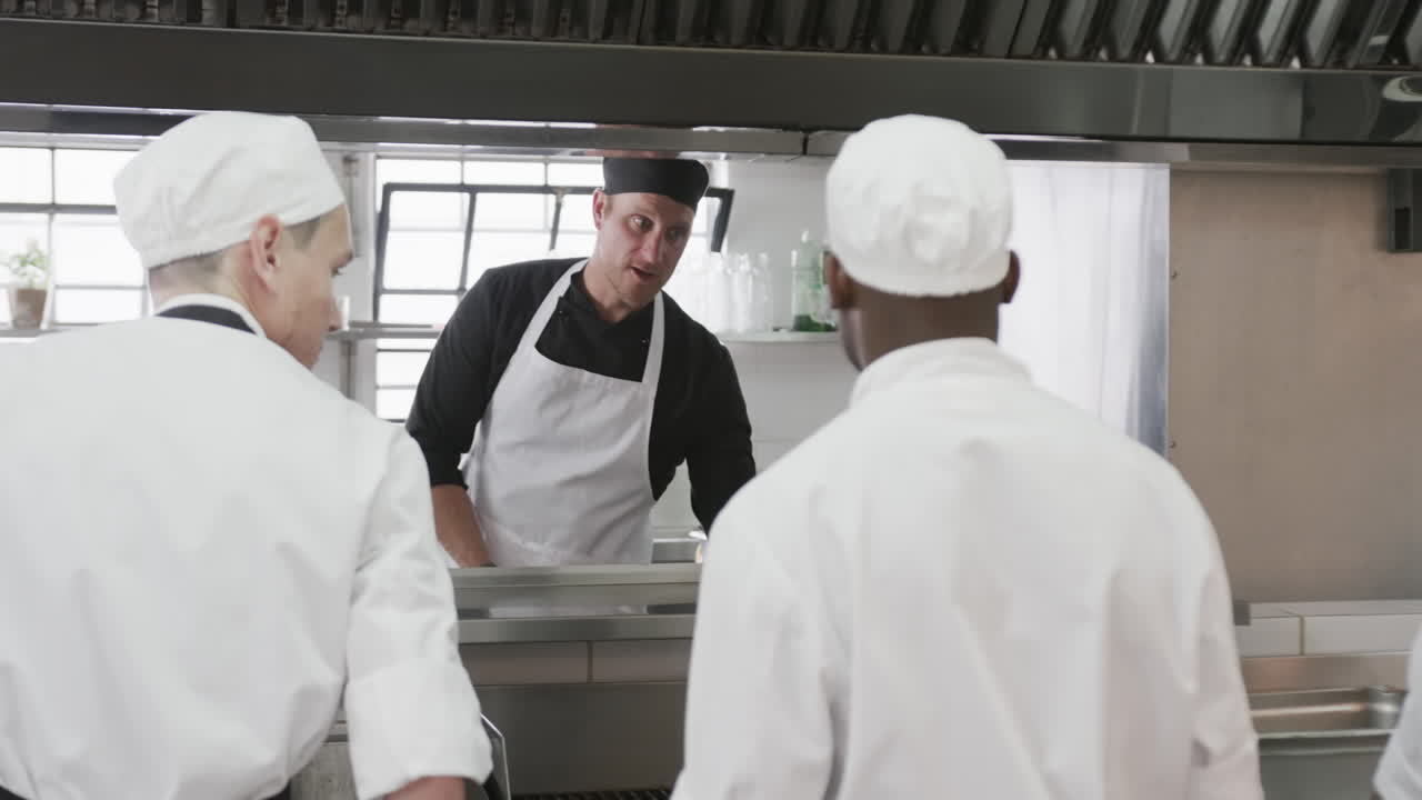 cocinero masculino enfocado instruyendo a los cocineros masculinos en prácticas en la cocina, cámara lenta
