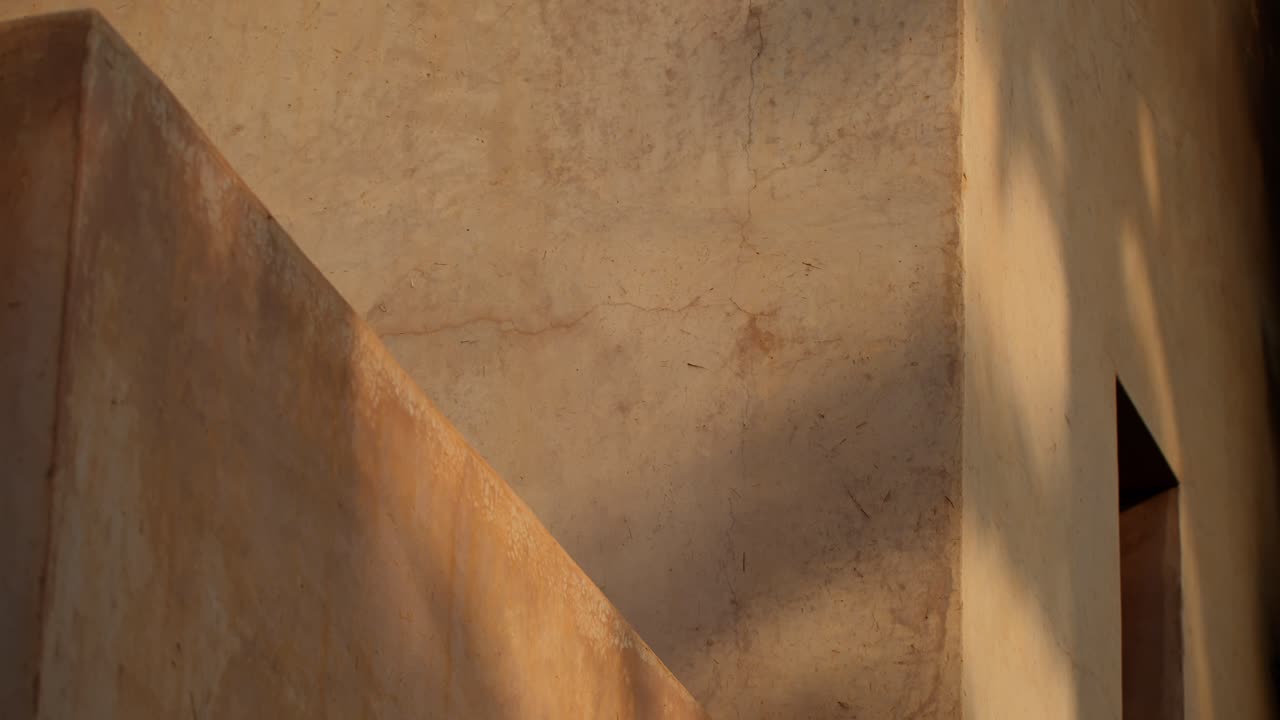 Close-up shot of classic Moroccan architectural details with sunlight casting tree shadows on the building facade in Marrakech, Morocco, showcasing texture and light play