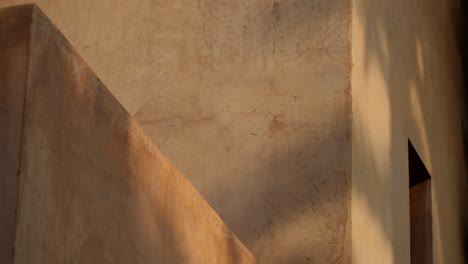 close-up shot of classic moroccan architectural details with sunlight casting tree shadows on the building facade in marrakech, morocco, showcasing texture and light play