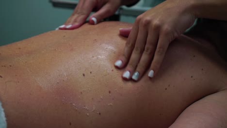 masseur's hands massaging the back and shoulders of an adult man with scrub.- close up shot