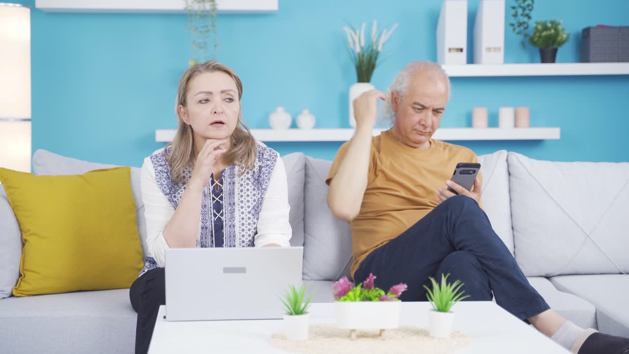 결혼한 부부가 노트북과 전화기로 시간을 보내고 있습니다. 집에서 기술을 사용합니다.