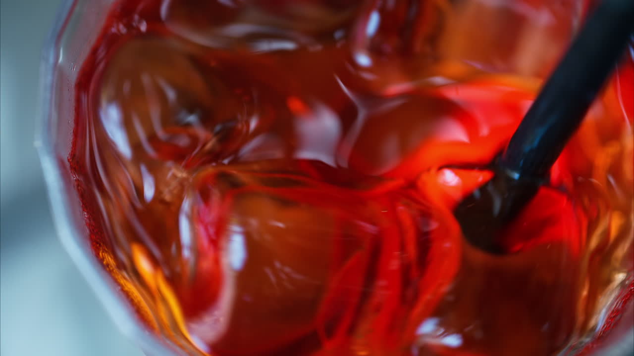 Primo piano di un cocktail Negroni mescolato con una cannuccia nera