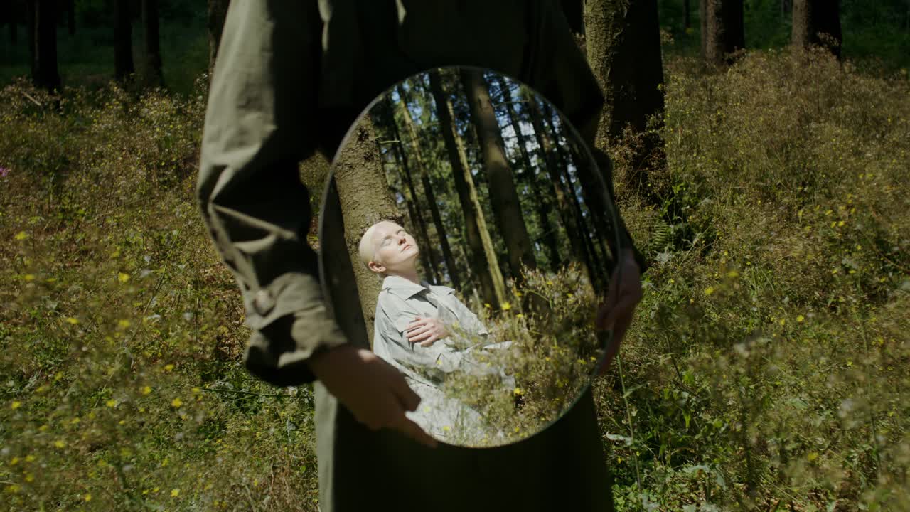 Woman holding a mirror in a forest