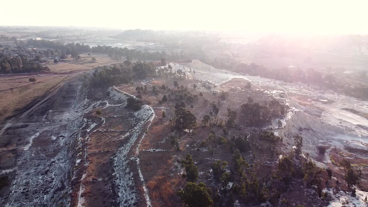 tiro aéreo de drones rastreando hacia atrás sobre un viejo basurero abandonado durante el amanecer en un hermoso día, benoni, sudáfrica