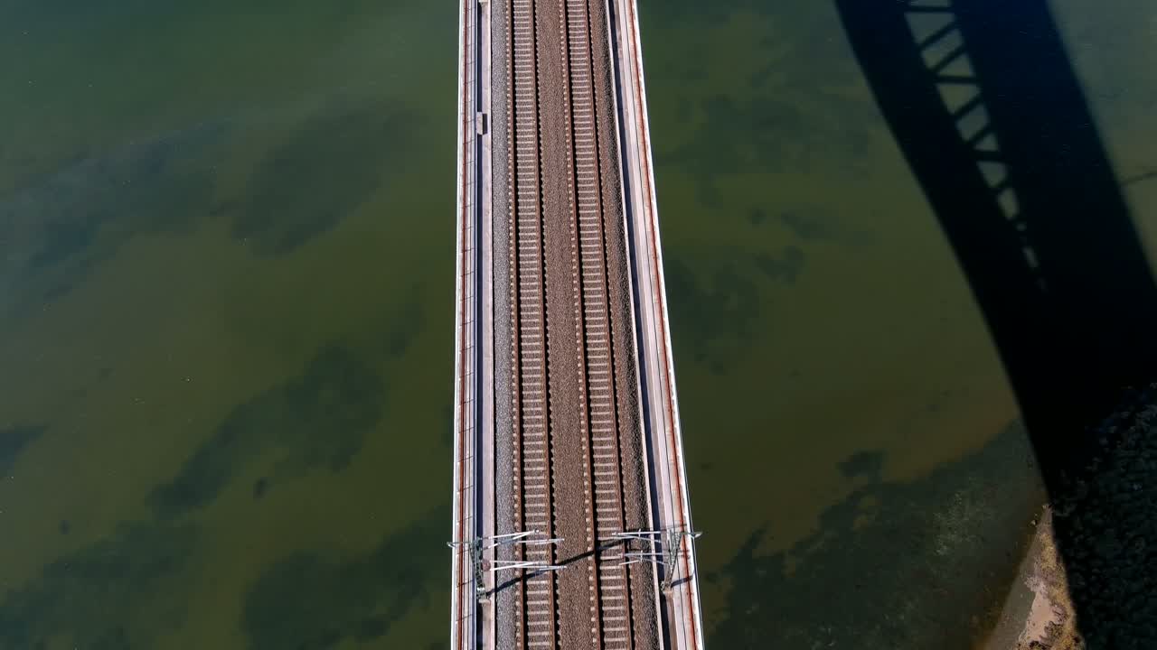 volando sobre el centro del puente del ferrocarril sobre la marisma y el agua azul turquesa del río ulla en un día soleado, rodando un dron disparado hacia adelante, catoira, galicia, españa