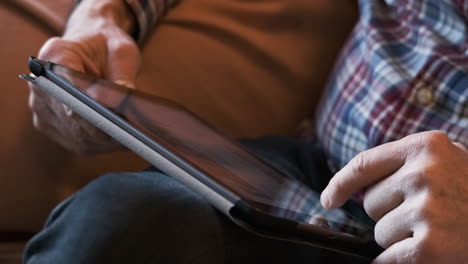 man scrolling through his newsfeed on a tablet - close up