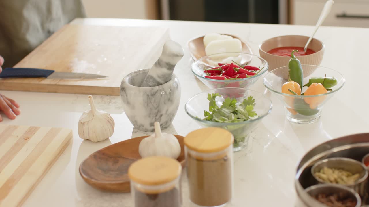 Left hand is entering and resting on kitchen counter by marble mortar, starting recipe prep