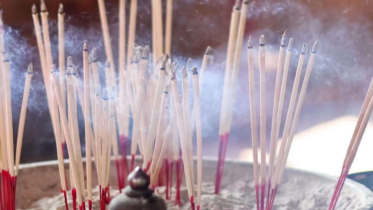 A detailed view of incense sticks burning and releasing smoke in a serene setting.