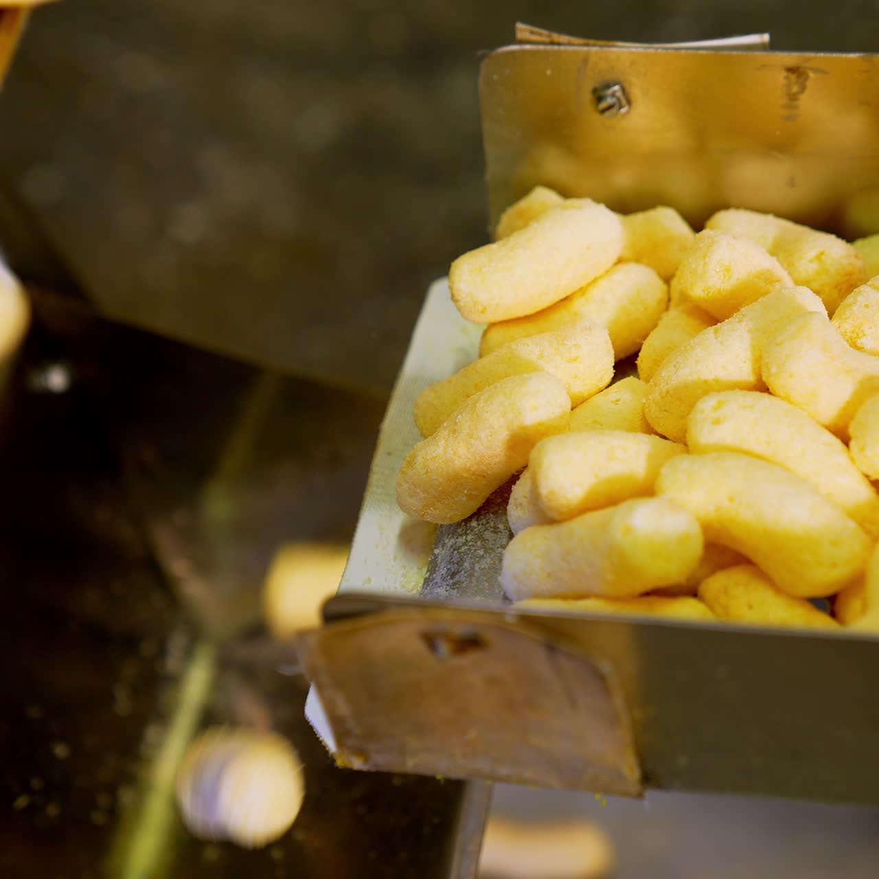 Nutritious crunchy corn product on the conveyor belt. Process of sweet snacks manufacturing at factory. Close up