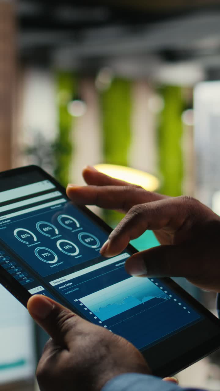 Vertical Video Close up of black employee engages in charts analysis session on tablet