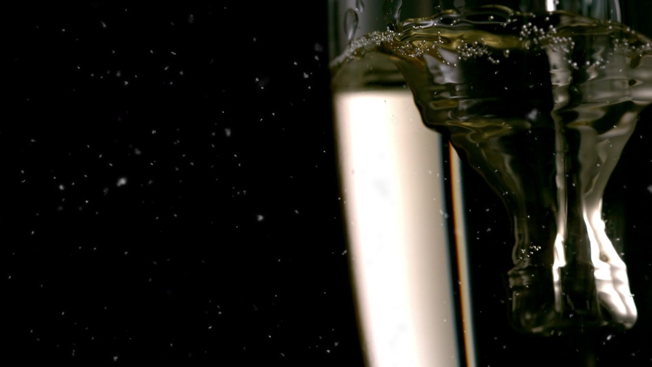 Animazione di coriandoli che cadono su bicchiere di champagne su sfondo scuro