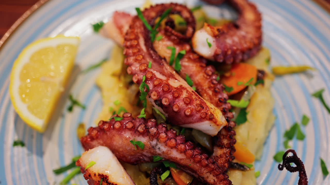 Close up of grilled octopus on a puree and a piece of lemon at a restaurant