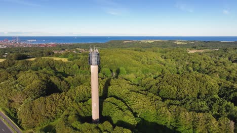 an aerial view of a tower built in a wooded area on a sunny summer evening