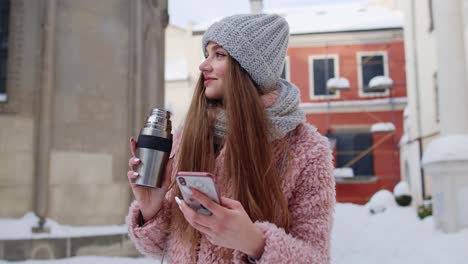 Traveler-woman-holding-mobile-phone,-chatting-with-friends-and-family,-drinking-hot-drink-tea