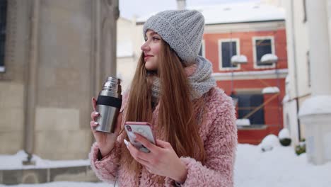 traveler woman holding mobile phone, chatting with friends and family, drinking hot drink tea