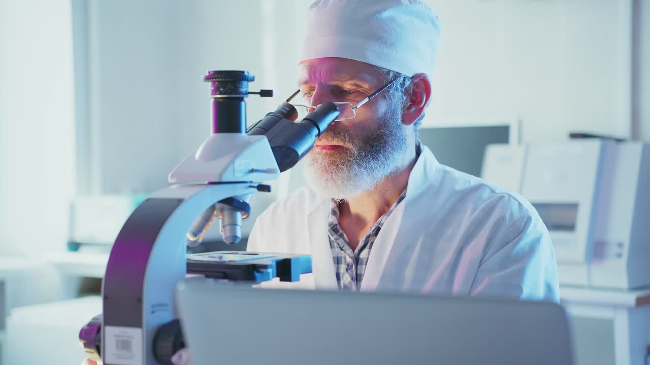 Focused Scientist Working with Microscope and Laptop in Modern Lab