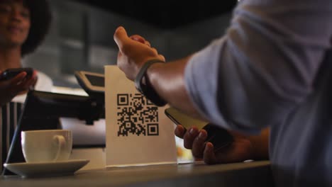 mixed race man giving african american female cafe worker his smartwatch in order to pay