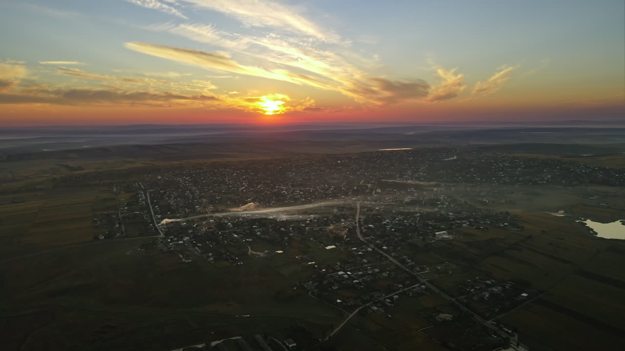 Aerial drone view of village in Moldova at sunset. Few columns of smoke from fires, wide fields