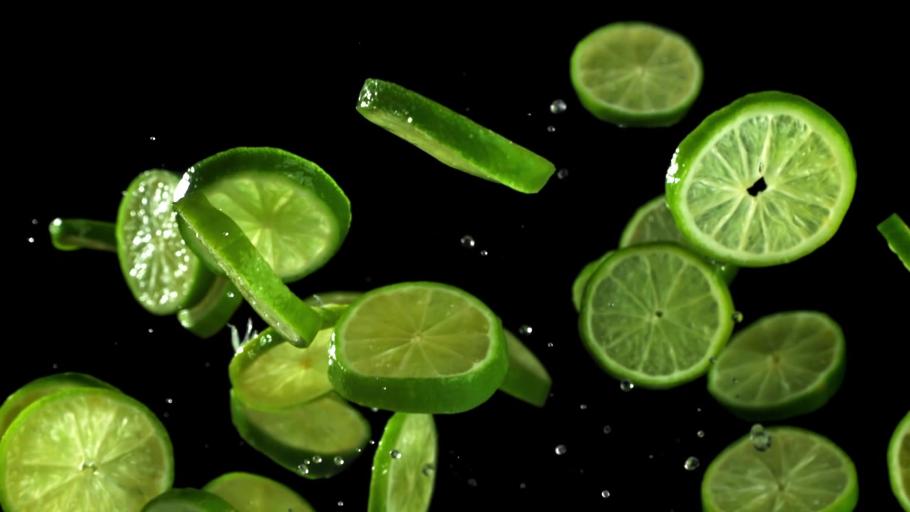 Fresh Lime Slices Falling and Splashing with Water on Black Background