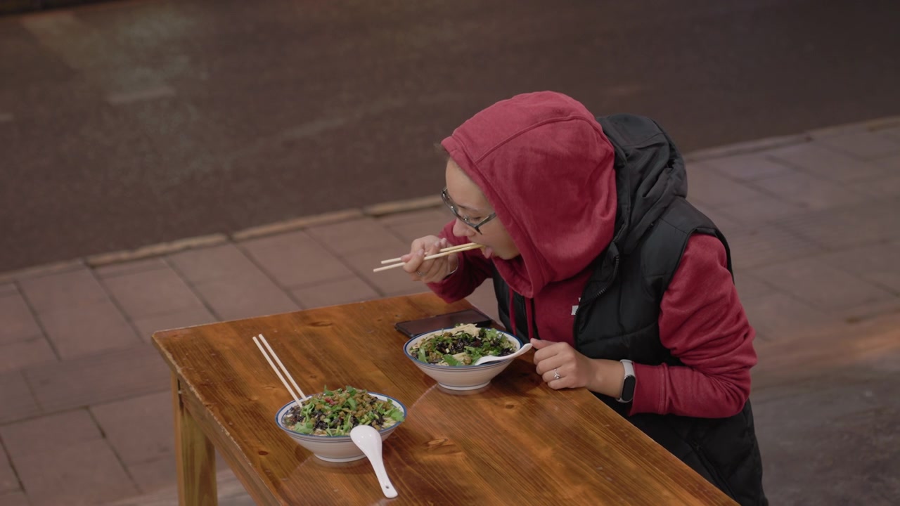 Adegan makan malam sendirian. Wanita makan sendirian di luar ruangan. Jalan-jalan sore berakhir dengan pengalaman makan yang tenang. Wanita Asia menikmati hidangan tenang setelah jalan-jalan malamnya.
