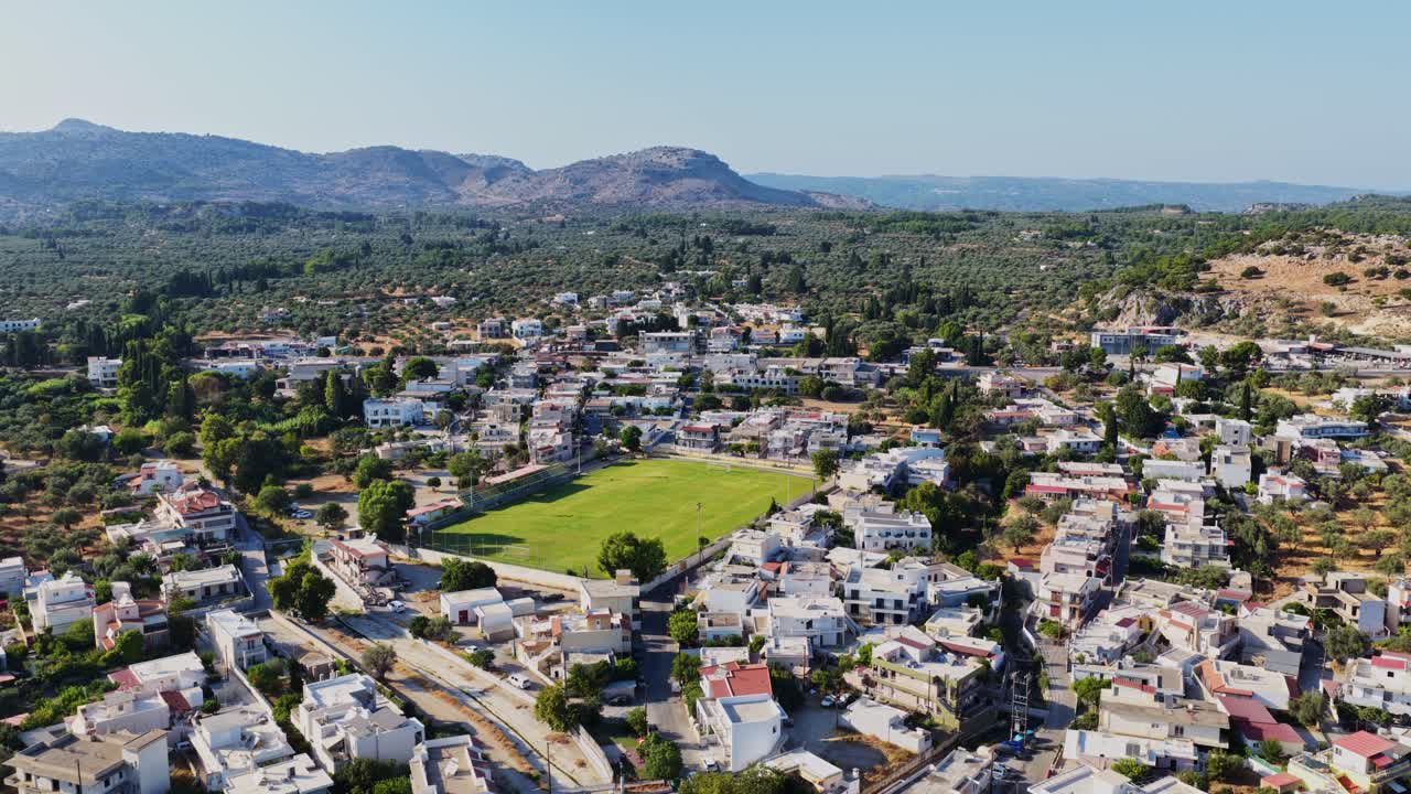 Aerial View of a Town with Green Football Field and Mountains