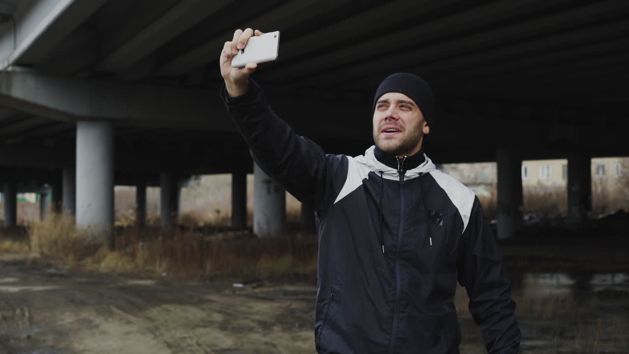 Mann macht ein Selfie unter einer Brücke