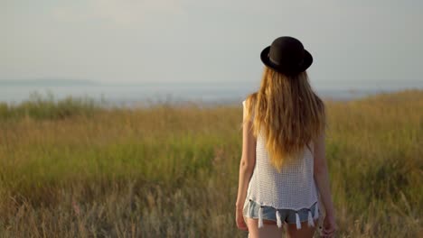 une femme dans un champ au coucher du soleil.