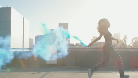 una mujer joven bailando afuera con una granada de humo al atardecer en el garaje del techo