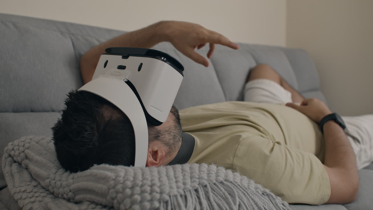 Man lays on sofa wearing VR headset while interacting with virtual content mid-air