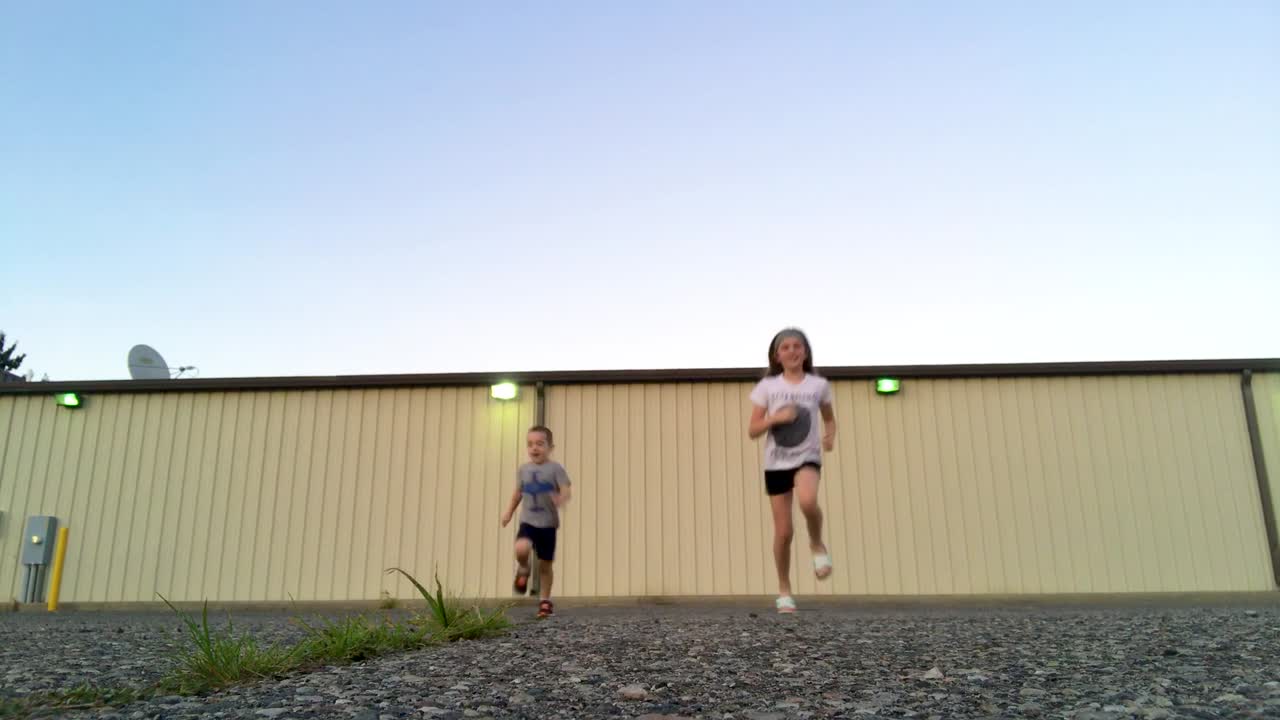 A young boy and girl run away from and toward camera.