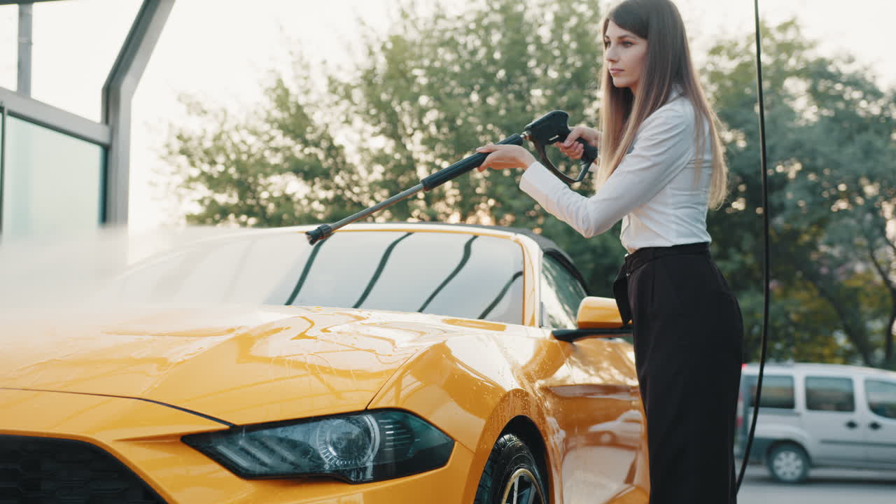 женщина стирает желтую кабриолетную машину в автомойке
