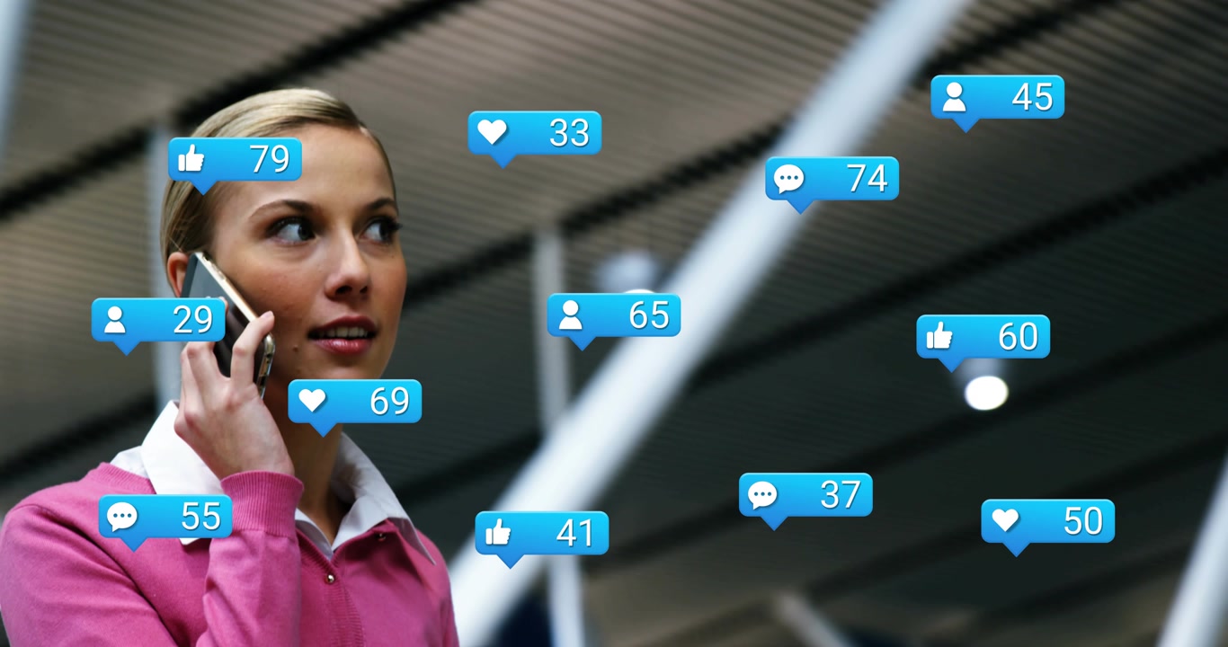 Woman speaking on phone in atrium generating social media badges multiplying around her and smiling