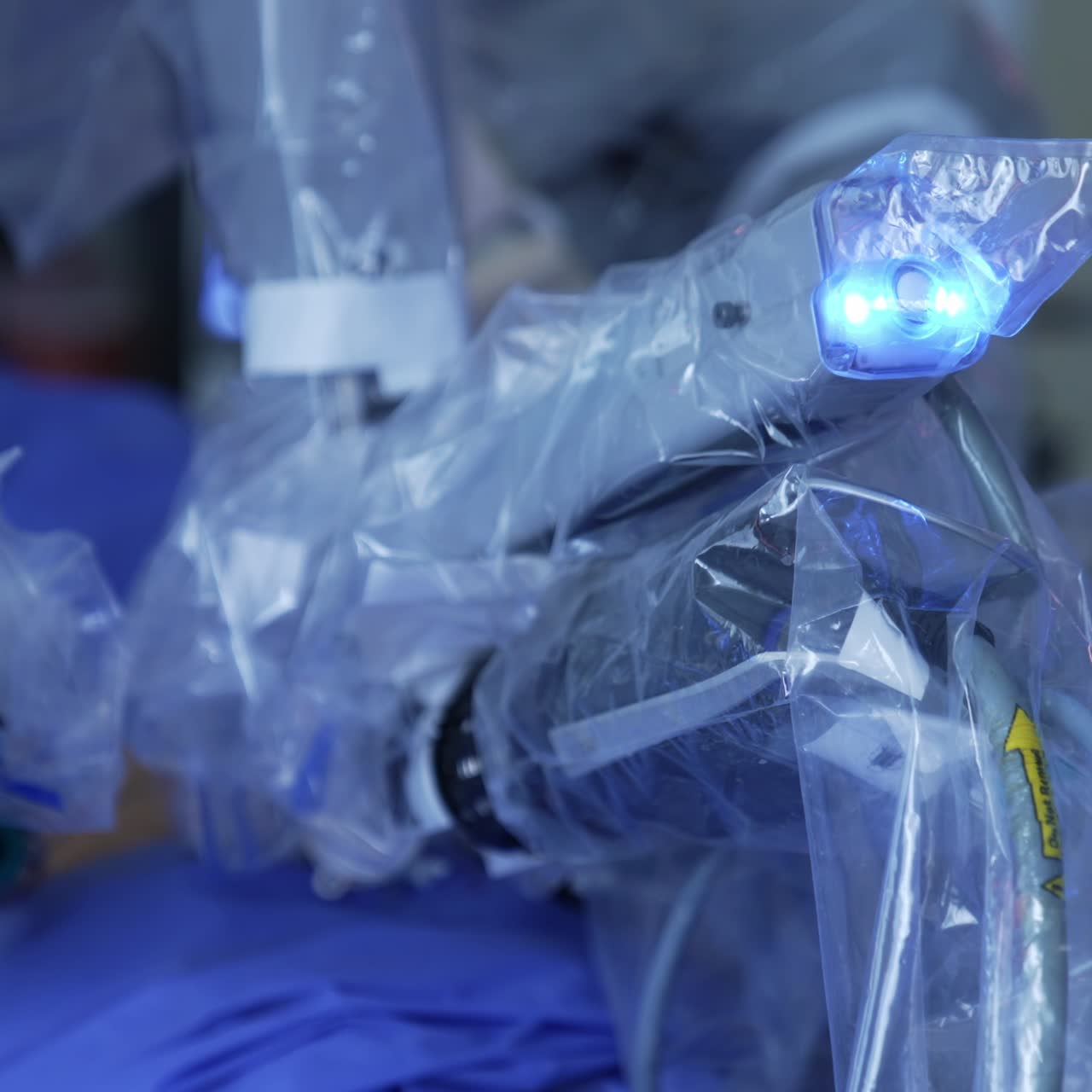 Futuristic equipment in plastic cover for sterility moving at operation. Close up. Hands of surgeon in latex gloves holding a tool