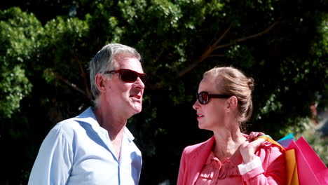 Happy-couple-chatting-and-looking-around-holding-shopping-bags