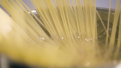 close-up slomo pan of spaghetti straws in pot of boiling water