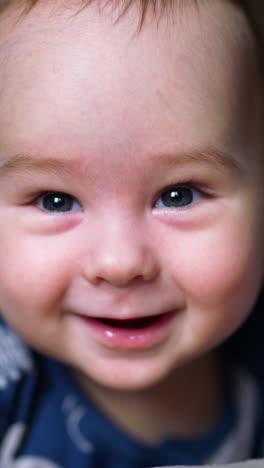 cute boy looks down with astonishment. beautiful caucasian kid smiling with his toothless smile. close up. vertical video