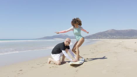 hombre enseñando mujer de pie en surf