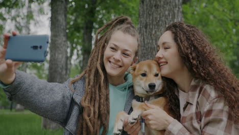 two women taking a selfie with their dog in a park