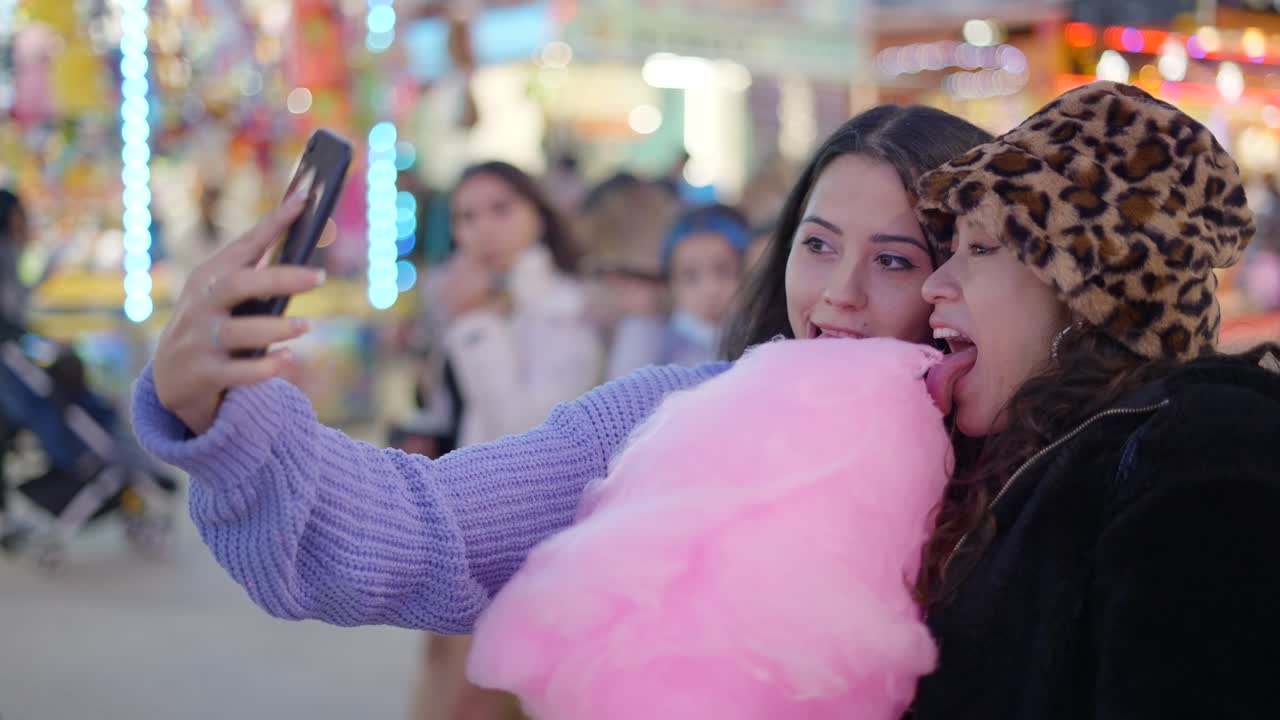 Two girls enjoying cotton candy at a funfair