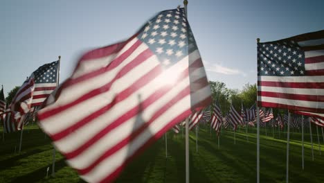 Amerikanische-Flaggen-Bei-Sonnenuntergang-In-Zeitlupe,-Nahaufnahme-Mit-Sonnenstrahlen