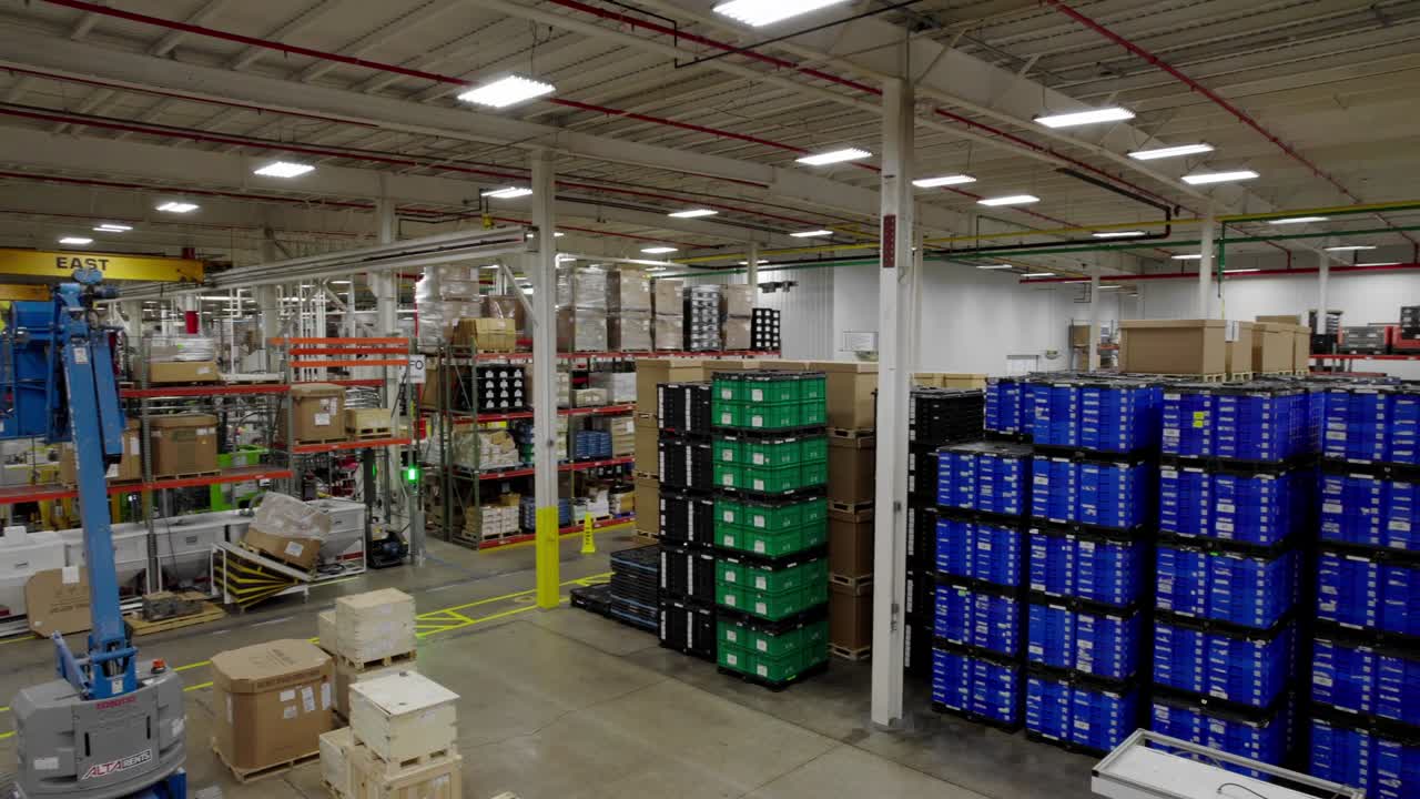 Wide pan of stacks of products in warehouse of tech factory, Michigan