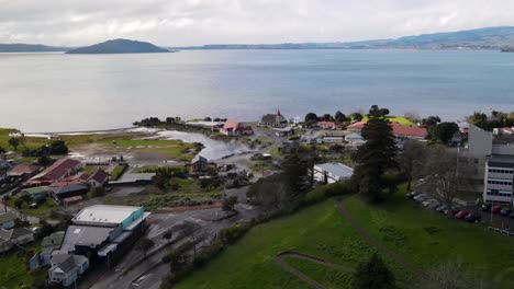 Drone-fly-to-Ohinemutu-Maori-living-historic-village-with-meeting-building,-anglican-church-and-war-memorial,-beautifully-located-on-Lake-Rotorua-lakeside,-New-Zealand