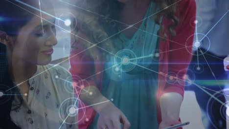 animación de una red de conexiones sobre dos mujeres diversas discutiendo sobre una tableta digital