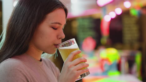 young woman drinking beer at a bar