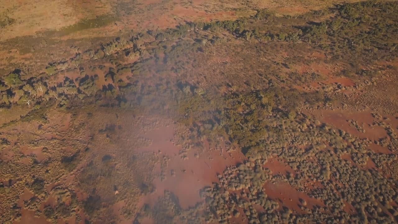 un dron aéreo volando sobre el vasto desierto australiano en un incendio de arbusto humeante